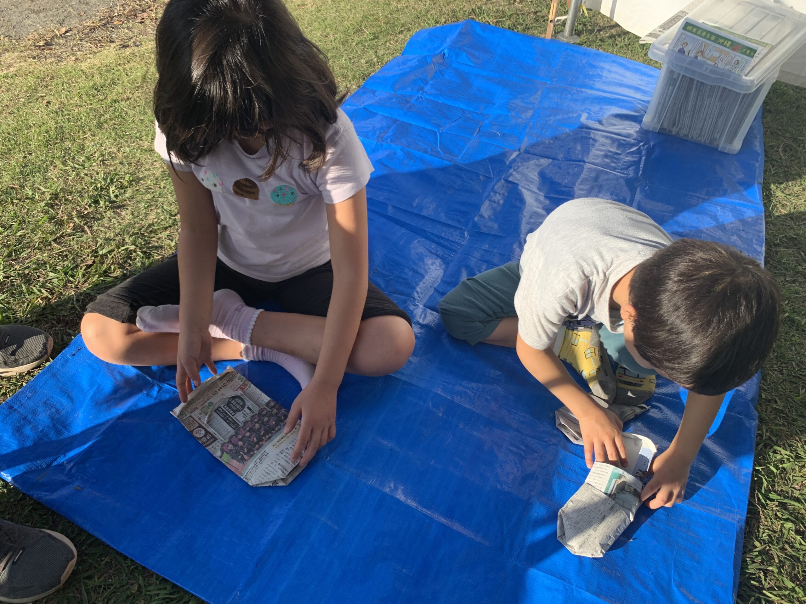 新聞紙スリッパを作る男の子と女の子